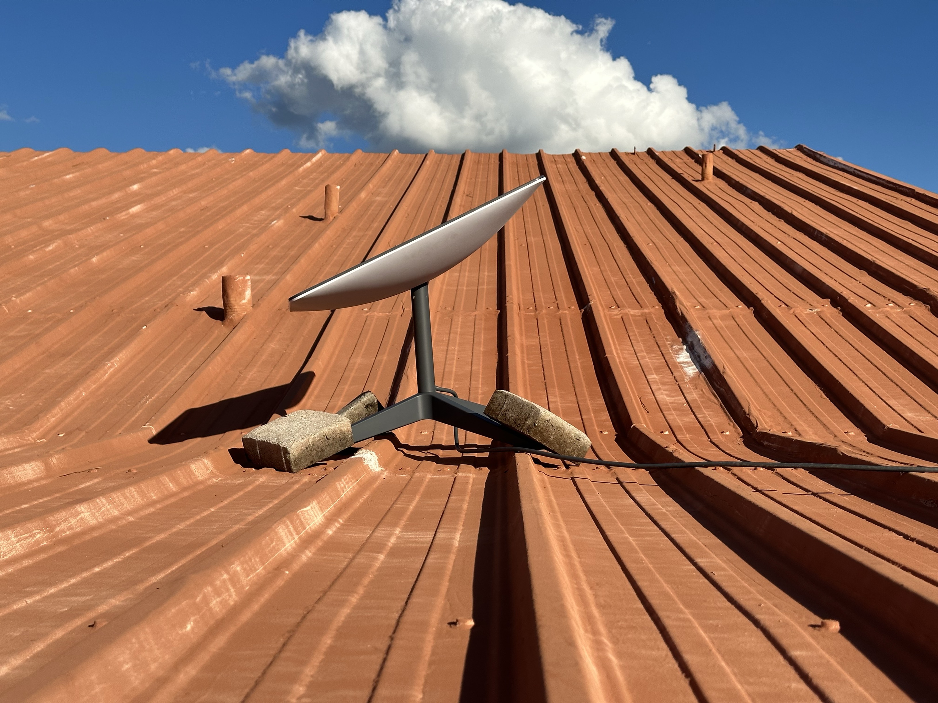 Starlink satellite dish mounted on red tile roof of rural home providing family internet access